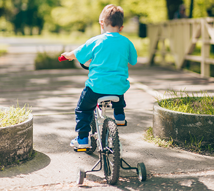 An image of a child riding a bike with training wheels